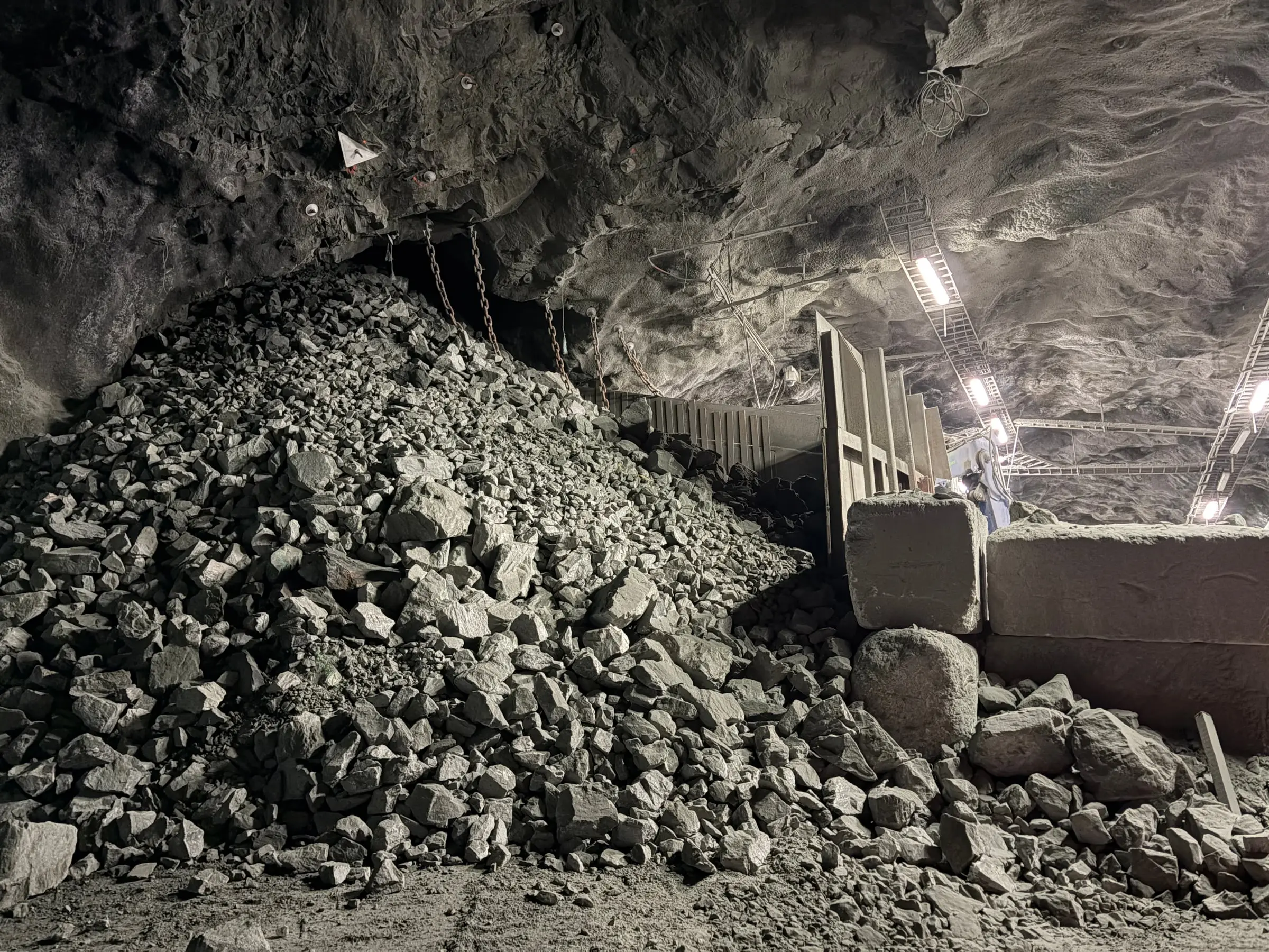 A heap of blasted rock under the rough ceiling of a mountain hall