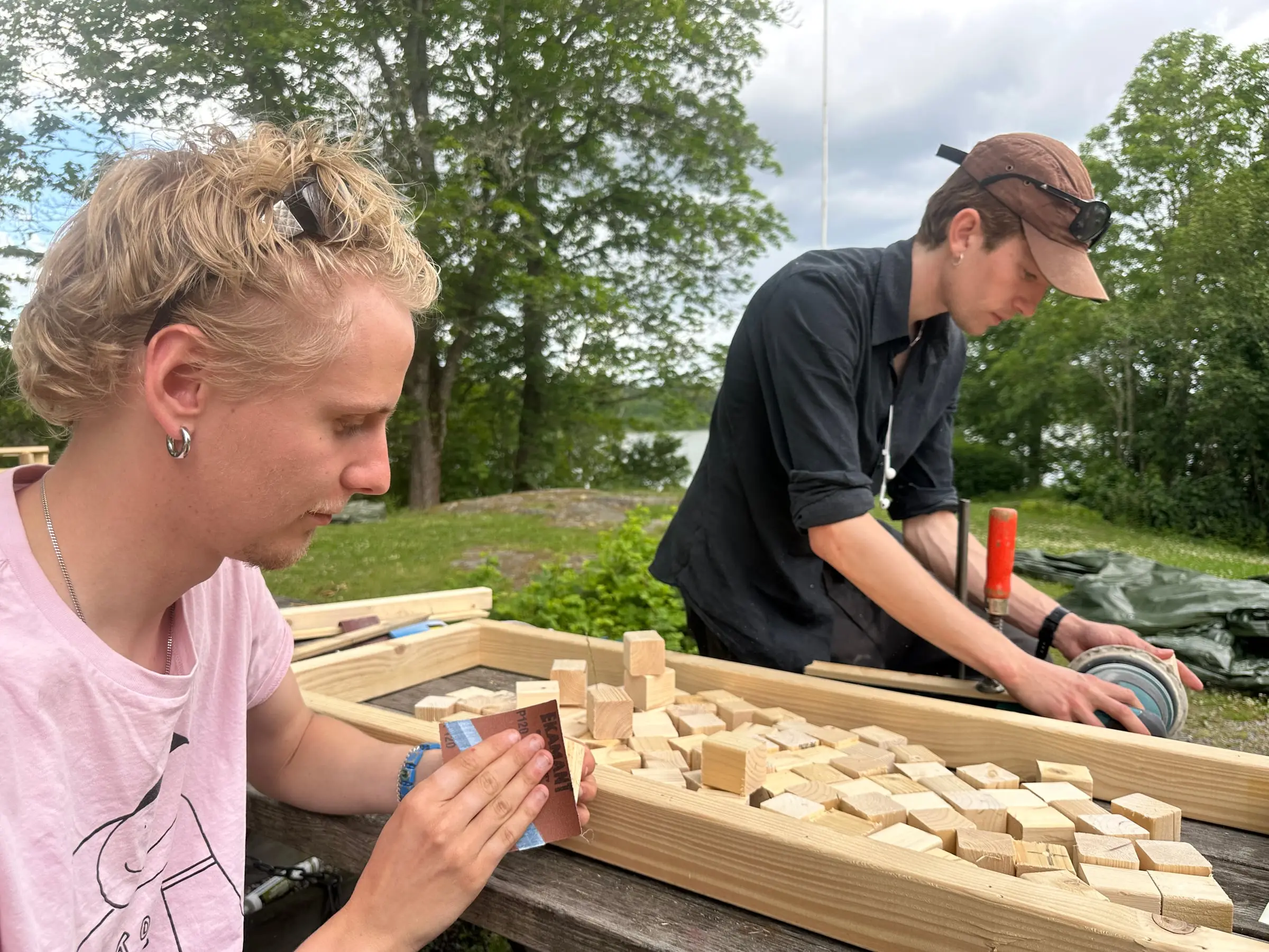 Two people at a table sanding small end-grain timber blocks