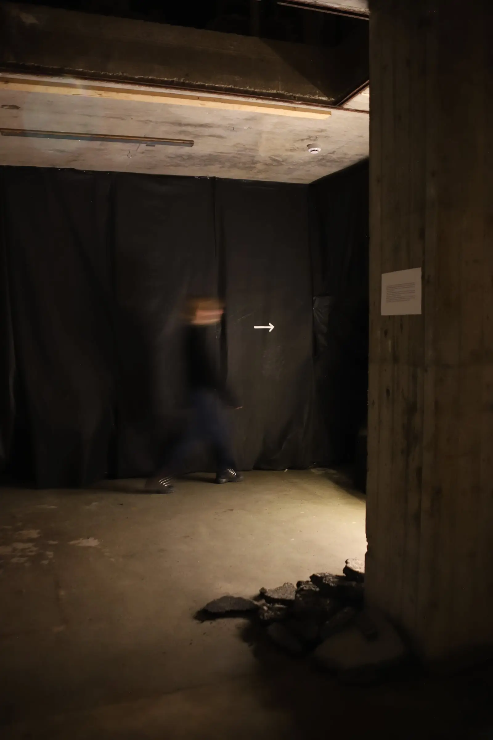 A dark opening in black fabric, a blurred visitor stepping into it