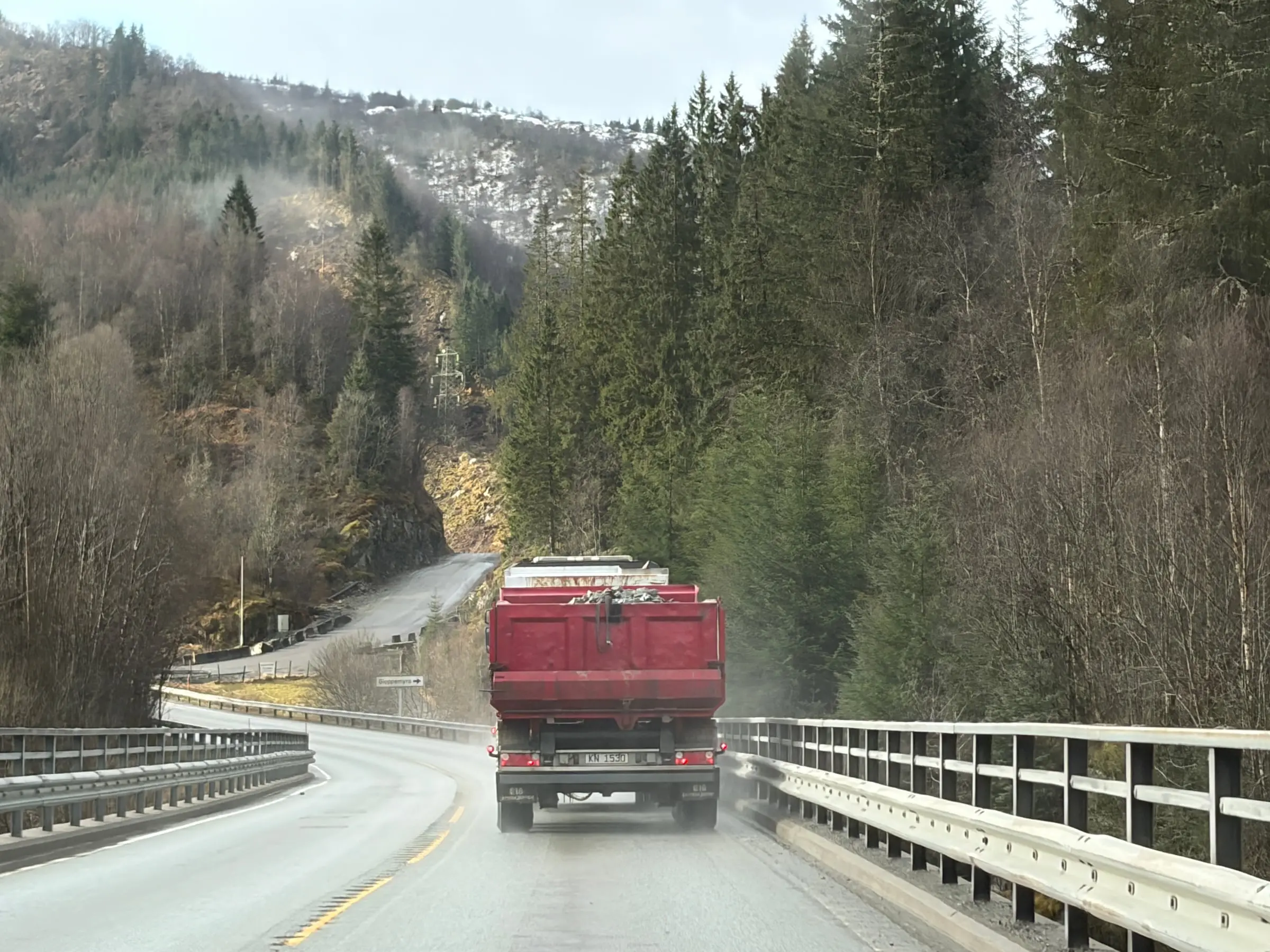 A red truck crossing a bridge through a wooded valley