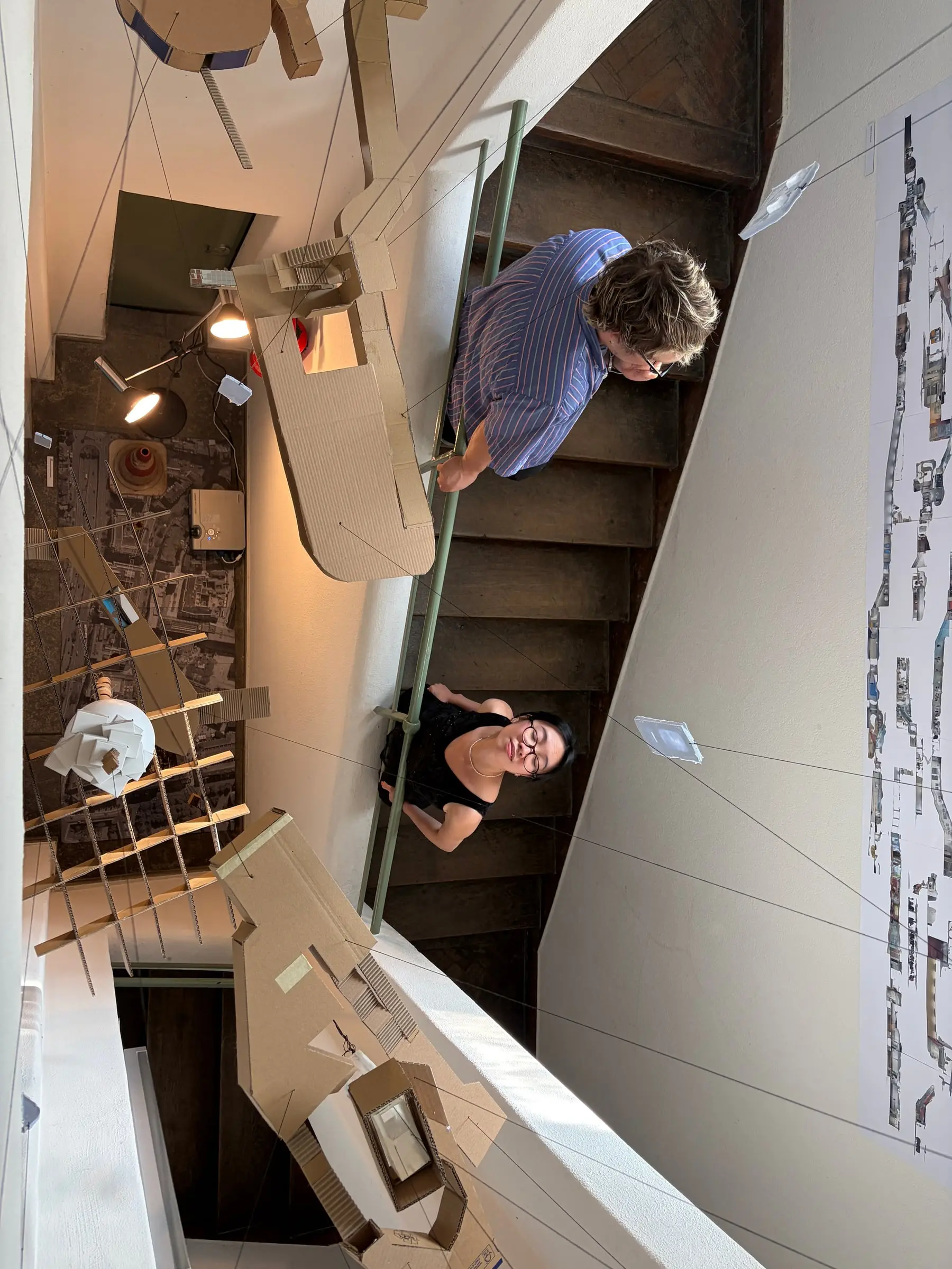 Two visitors on the stairs looking down at the model hanging between the flights
