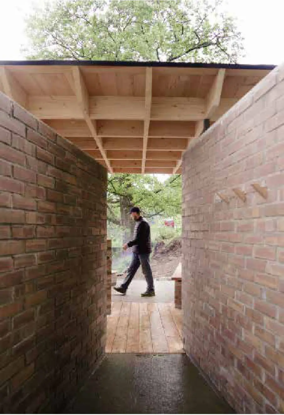 Narrow brick passage roofed in timber, with a person walking through at the far end