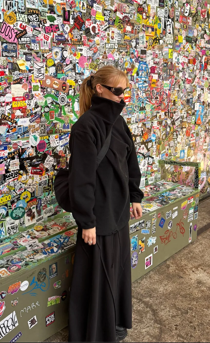Frida Irene Heldal Stray, standing in front of a sticker-covered wall