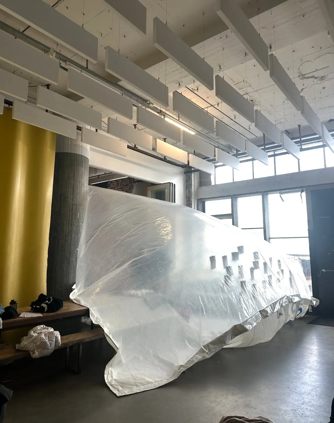 The inflatable lying along the windows of a hall with slatted ceiling and a yellow column