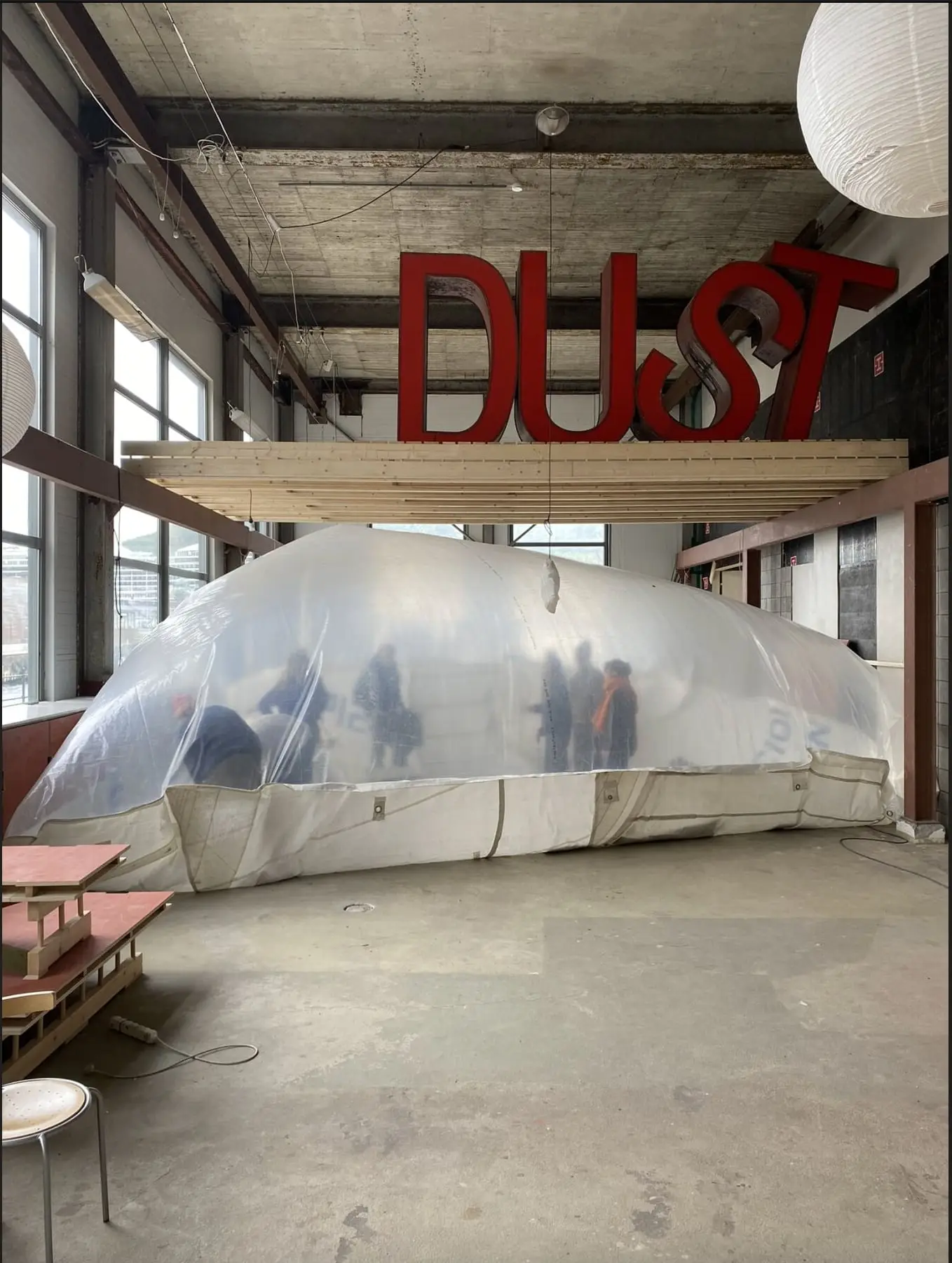 The translucent inflatable filling a workshop hall, a red DUST sign hanging above it