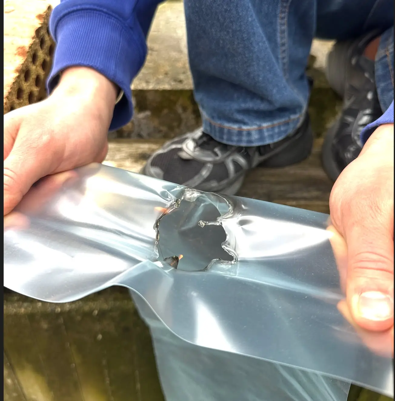 Two hands patching a tear in the clear plastic