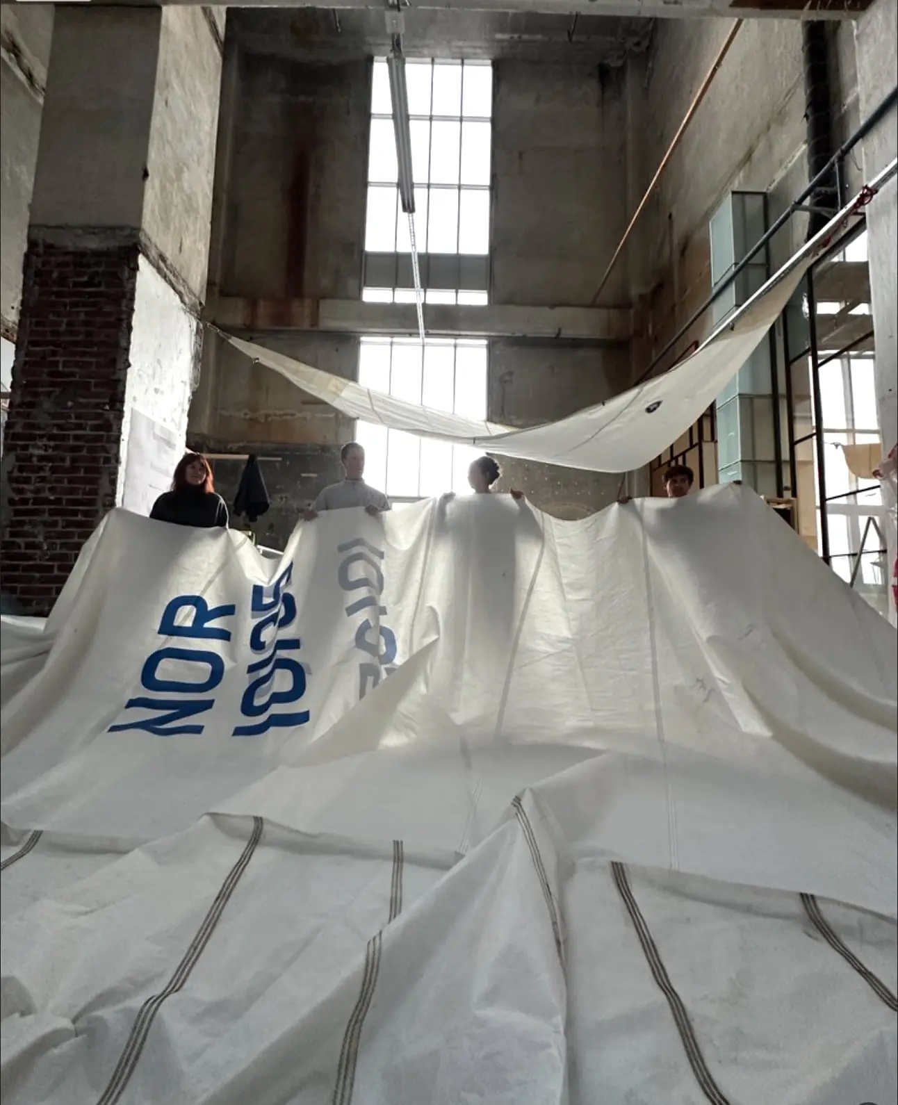 Old sails with printed lettering spread across a large workshop floor