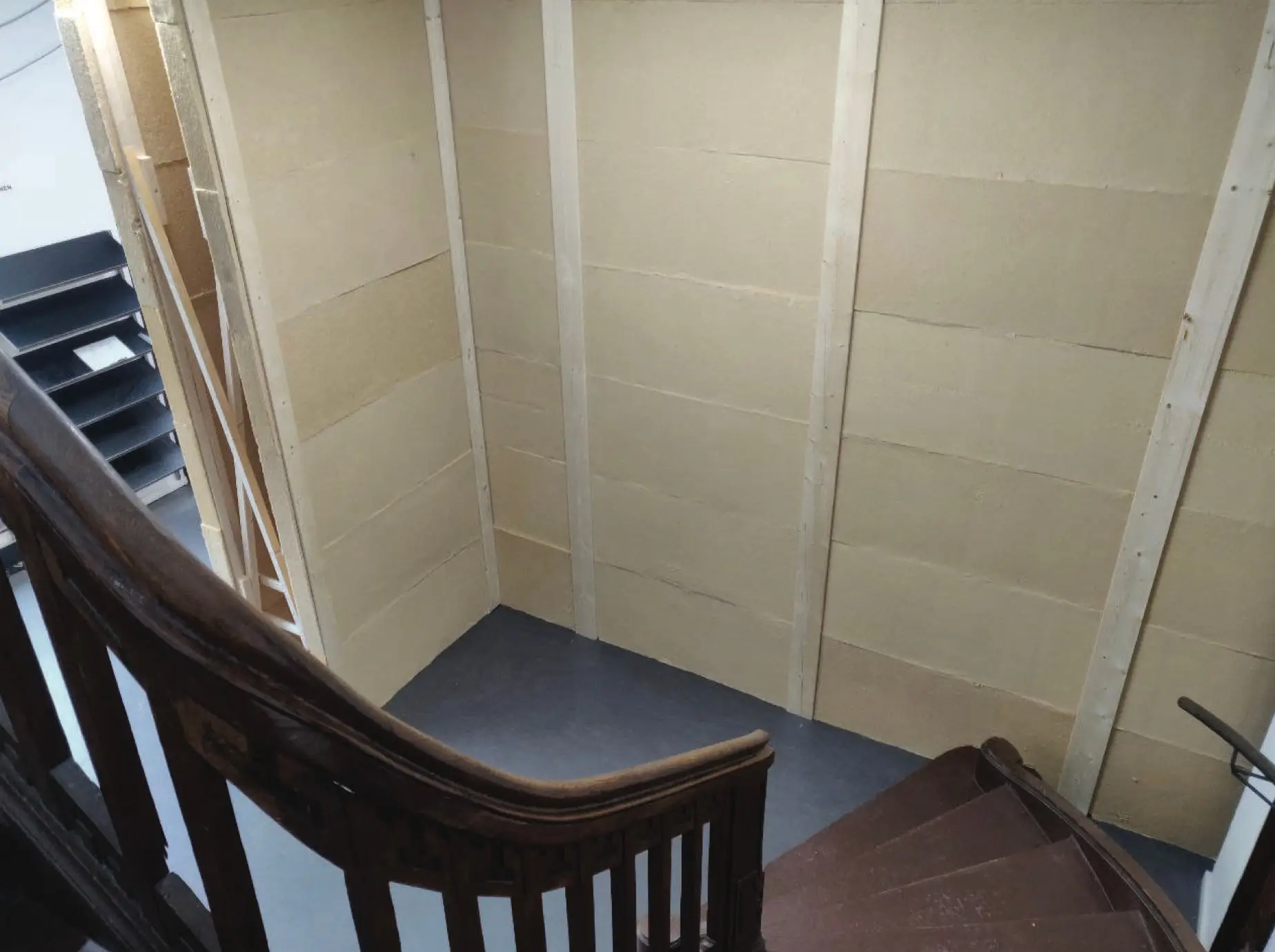 Looking down a wooden staircase into a stairwell lined with insulation boards and timber studs