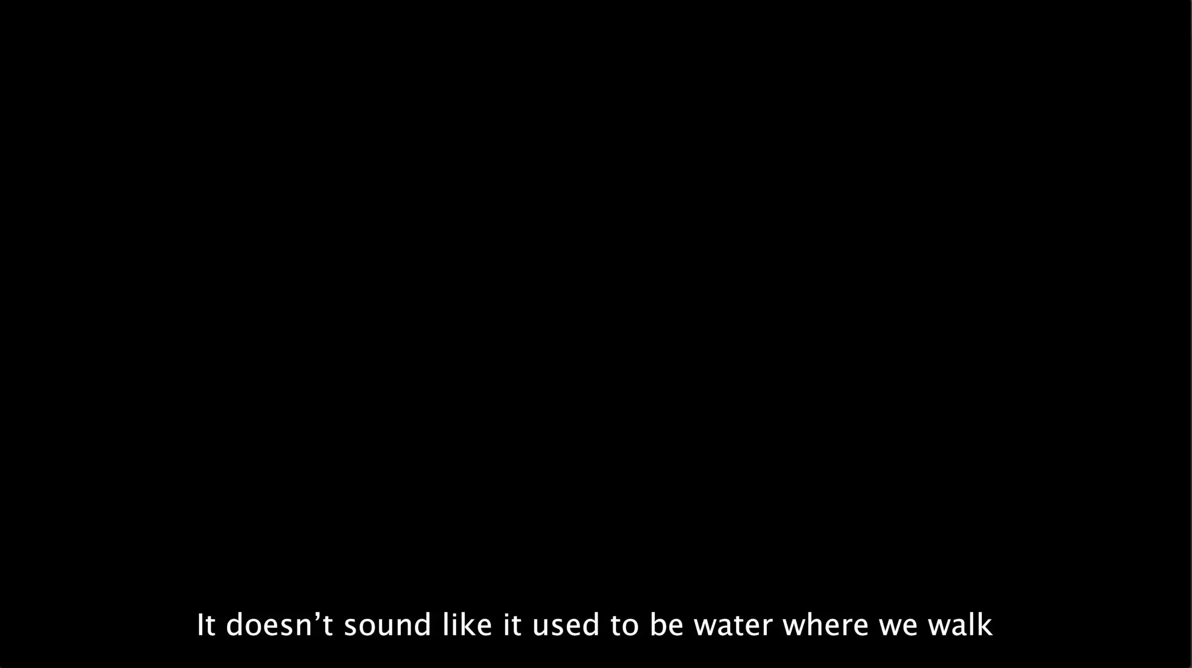 Black film frame with the subtitle 'It doesn't sound like it used to be water where we walk'