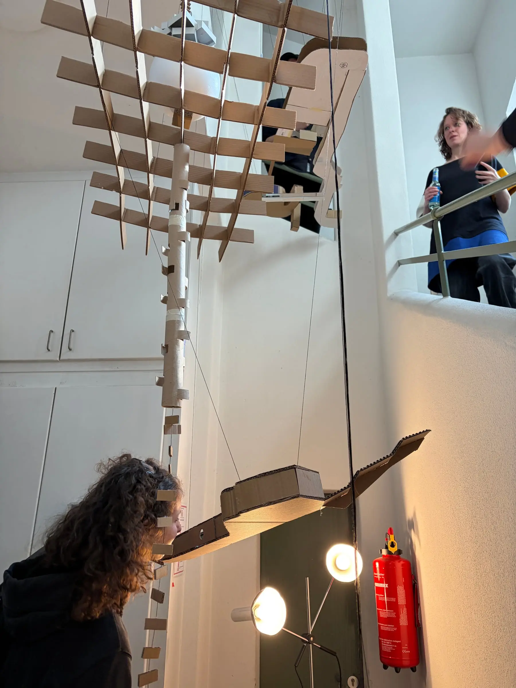 A visitor looking up into the hanging model of timber slats and cardboard